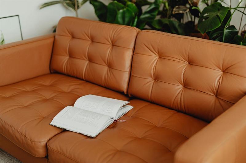Close-up view of a faux leather sofa with a focus on its texture and stitching, demonstrating how to deodorize faux leather couch using effective methods to try."